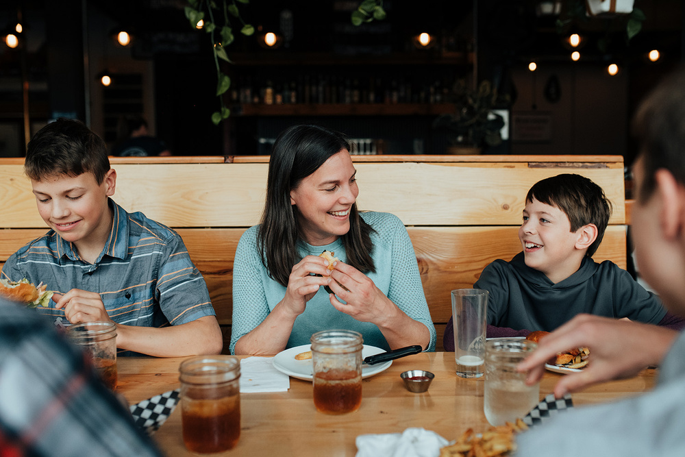 A Family sitting at a booth in a restaurant enjoying a meal.